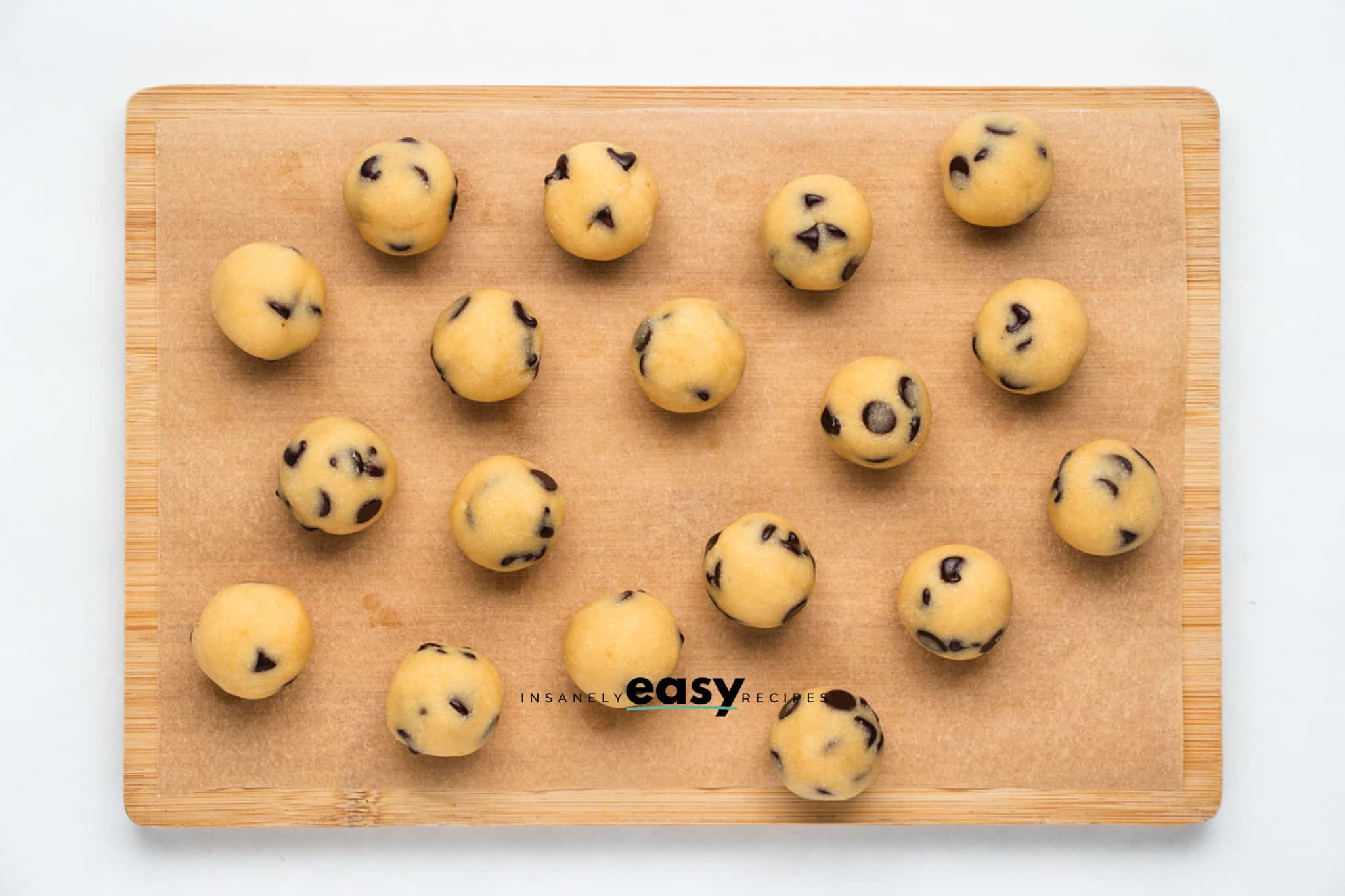 Top view photo of finished No Bake Cookie Dough Bites, on a wooden cutting board and ready to enjoy.