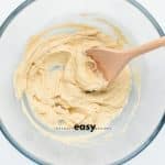 Top view photo of butter and sugar mixed together in a glass bowl until light and fluffy with a wooden spoon.