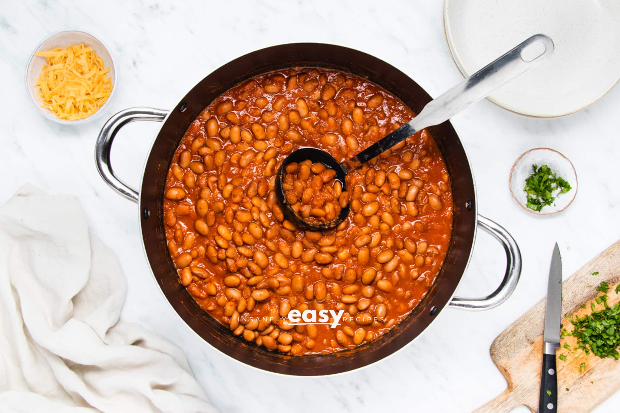 a large pot of beans. A ladle is holding up a serving of ranch beans.
