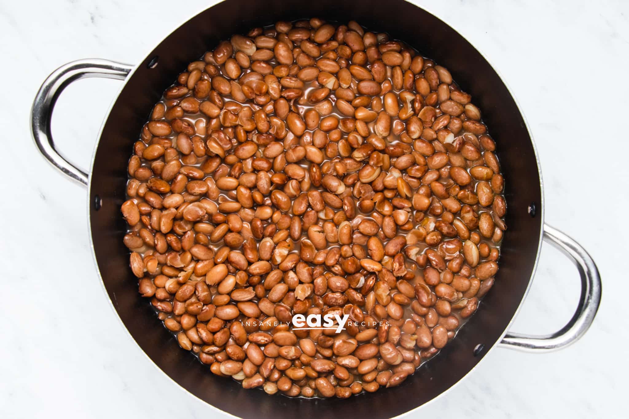pinto beans simmering in a saucepan.