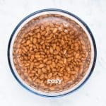 pinto beans soaking in a bowl of water.