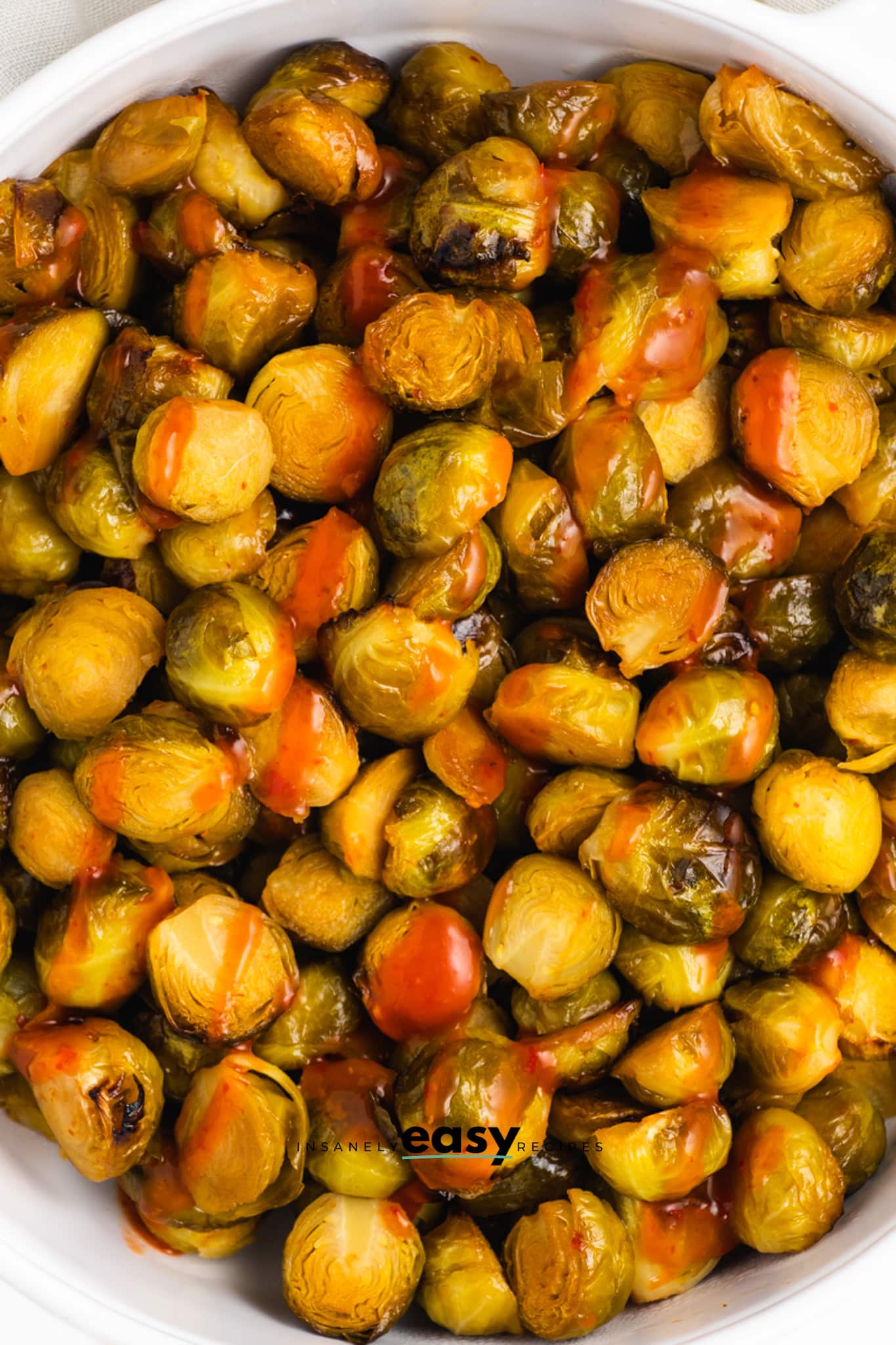 closeup view of roasted brussel sprouts with sriracha honey sauced drizzled over them.