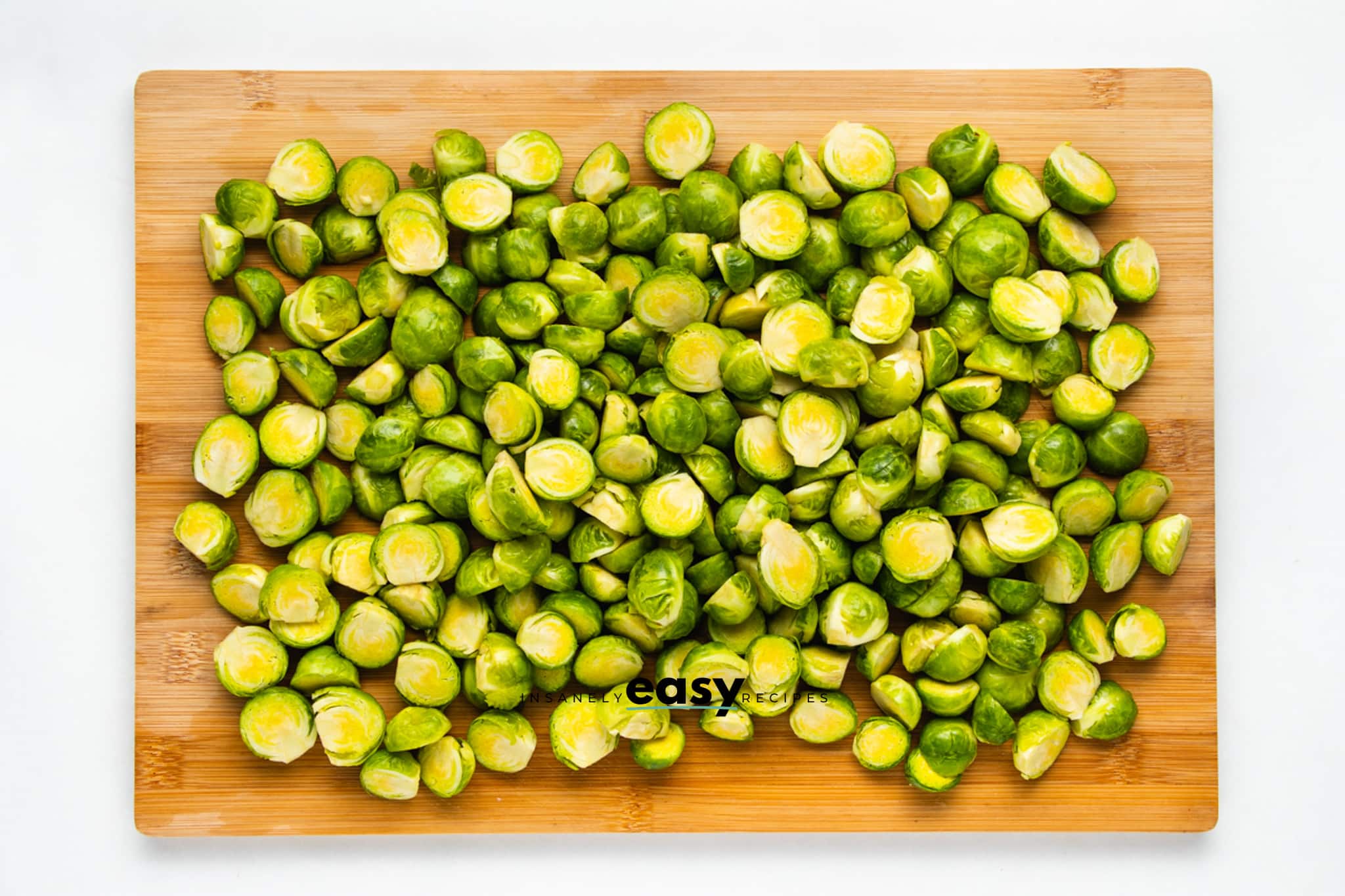 brussel sprouts trimmed and sliced on a wooden cutting board