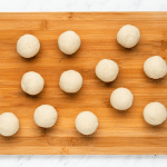 balls of tortilla dough on a wooden cutting board.