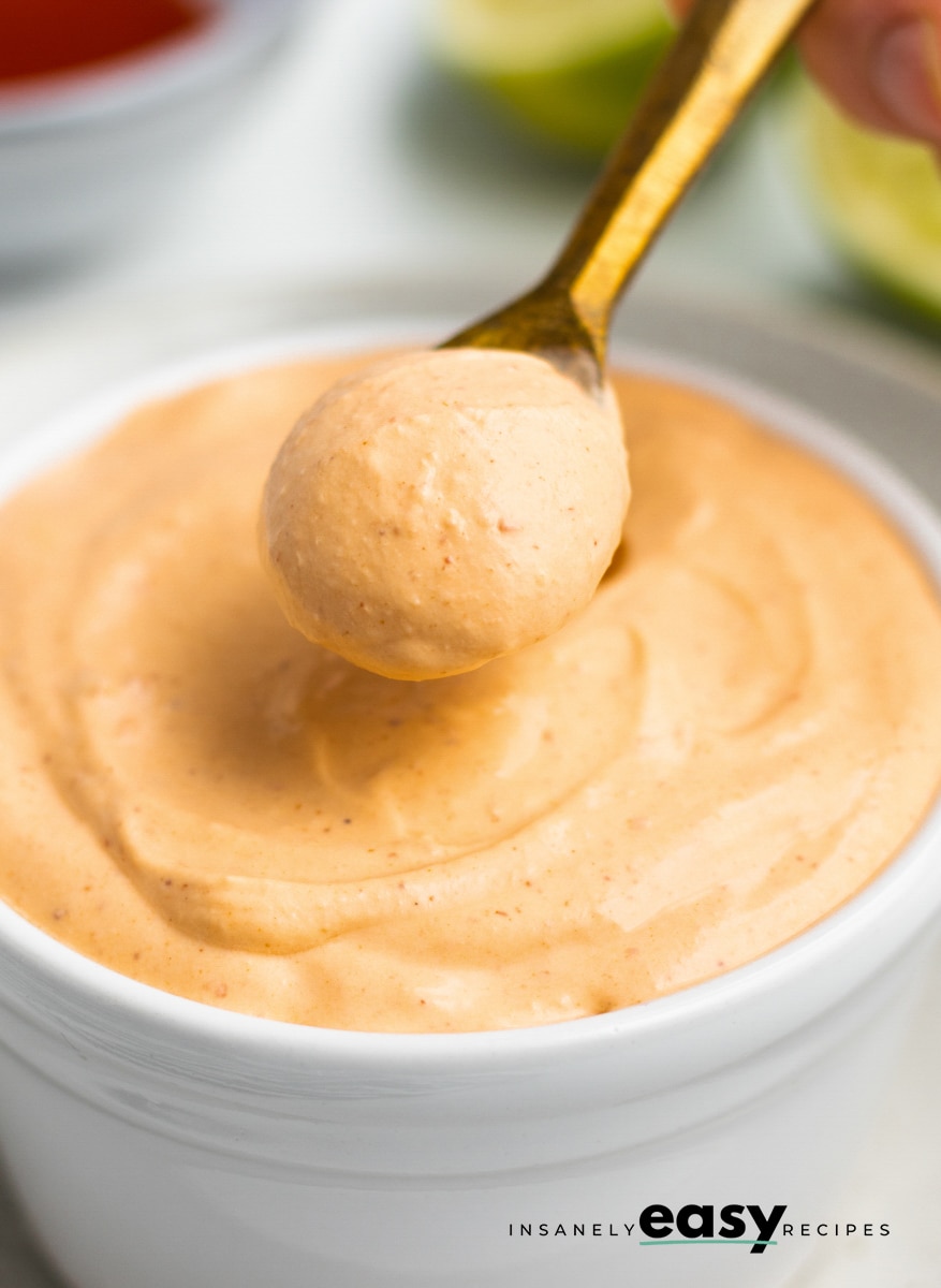 Creamy chile crema in a bowl. A gold spoon is serving it.