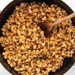 popcorn in a pot, coated with chili powder and butter, stirred with a wooden spoon.