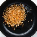 a large pot with oil and unpopped popcorn kernels in it.