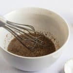 Photo of a white bowl with a wire whisk, mixing together the flax egg mixture.