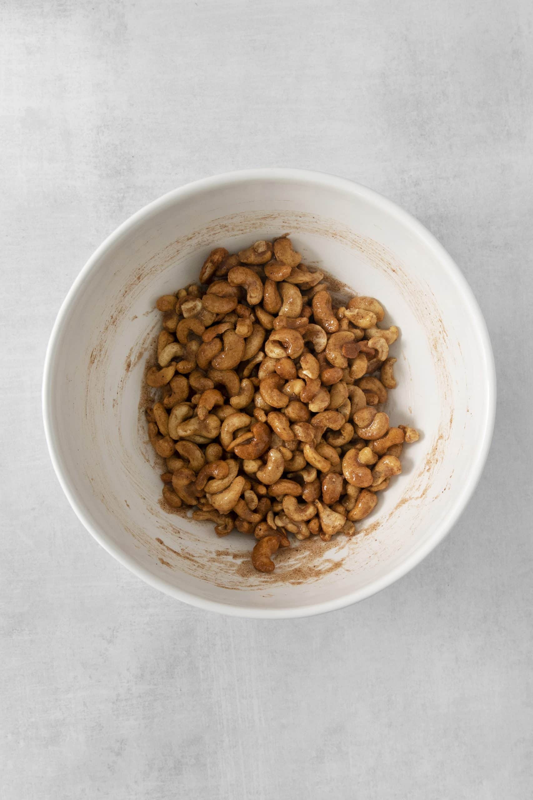 a mixing bowl of cashews coated with sugar and egg whites.