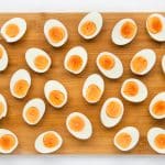 hard boiled eggs, peeled and cut in half, arranged on a cutting board.