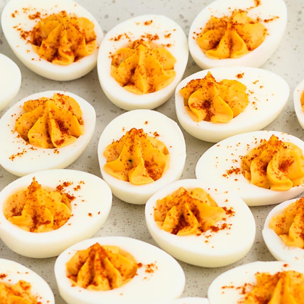 Hard boiled eggs filled with creamy deviled egg filling and topped with a sprinkle of paprika.